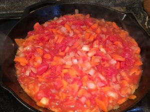 Simmering carrots, onions and diced tomatoes.